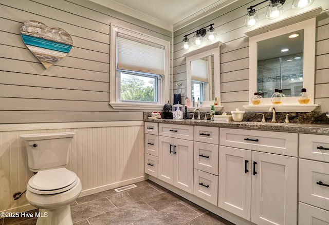 full bathroom featuring a sink, toilet, visible vents, wood walls, and ornamental molding
