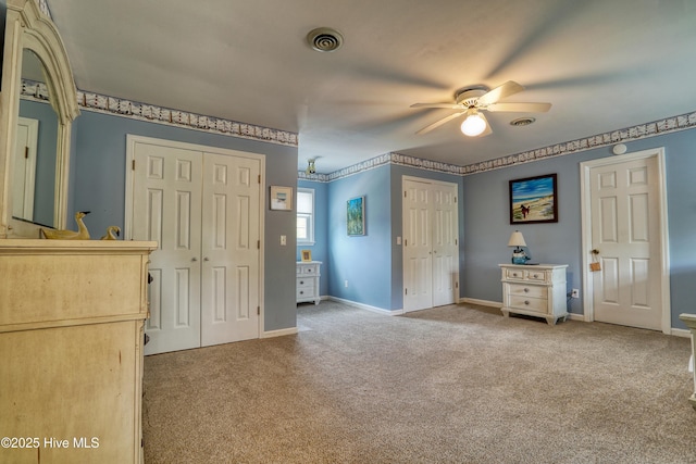 unfurnished bedroom with baseboards, visible vents, carpet floors, and multiple closets