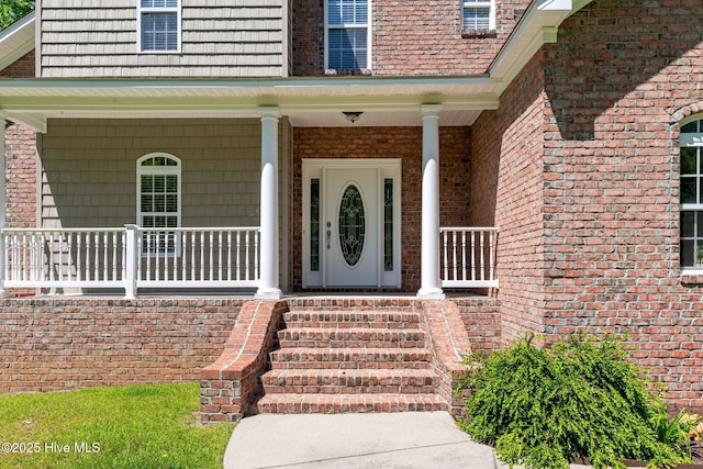 property entrance featuring a porch and brick siding
