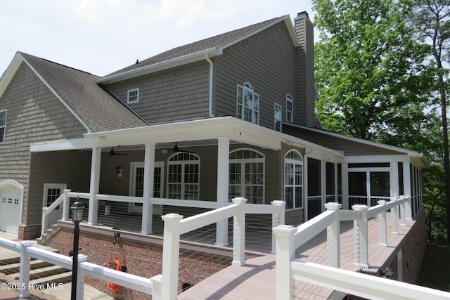 back of property featuring a chimney, a wooden deck, roof with shingles, and ceiling fan