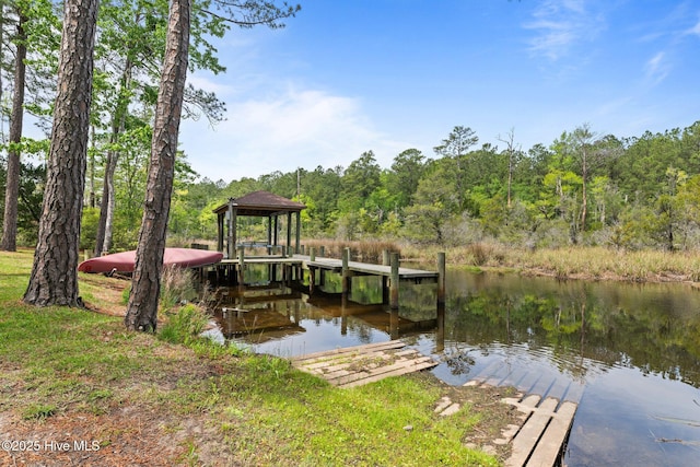 dock area with a water view, a gazebo, and a view of trees