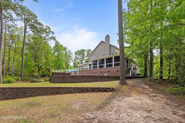 rear view of house with a sunroom and a chimney
