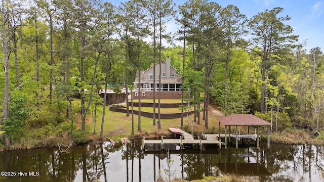 dock area featuring a yard, a wooded view, boat lift, and a water view
