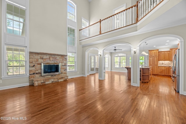 unfurnished living room featuring light wood-style flooring, a high ceiling, and arched walkways
