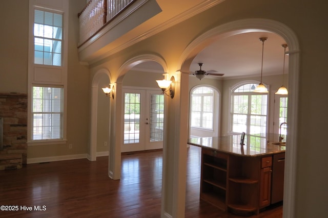 interior space featuring a wealth of natural light, arched walkways, and dark wood-style floors