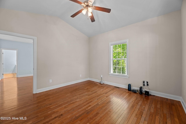 empty room featuring lofted ceiling, visible vents, ceiling fan, wood-type flooring, and baseboards