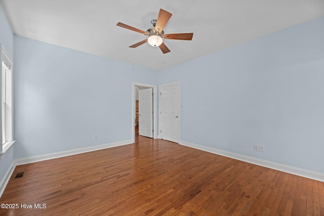empty room with visible vents, baseboards, ceiling fan, and hardwood / wood-style flooring