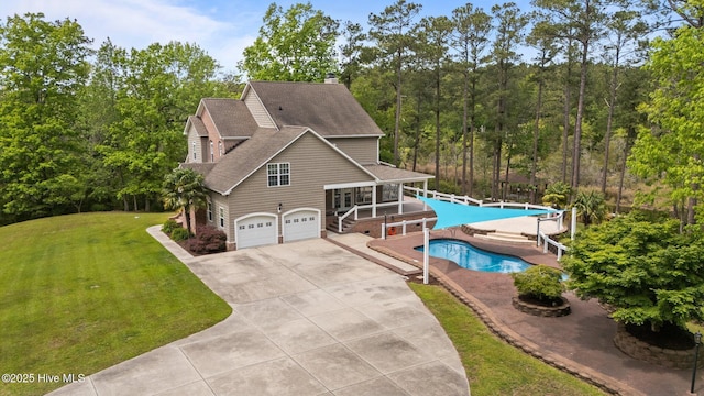chalet / cabin with a chimney, an outdoor pool, a garage, concrete driveway, and a front lawn