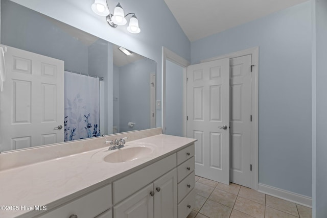 bathroom with baseboards, tile patterned flooring, vanity, and lofted ceiling