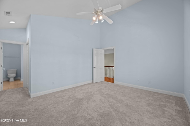 unfurnished bedroom featuring ensuite bath, high vaulted ceiling, visible vents, carpet floors, and baseboards