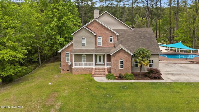 view of front of home with covered porch, a shingled roof, a chimney, and a front yard