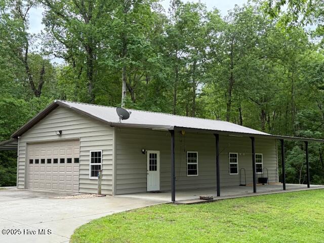 view of front of house featuring covered porch, concrete driveway, an attached garage, and a front yard