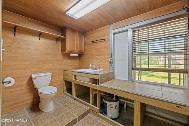 bathroom with toilet, a sink, tile patterned floors, wooden ceiling, and wooden walls