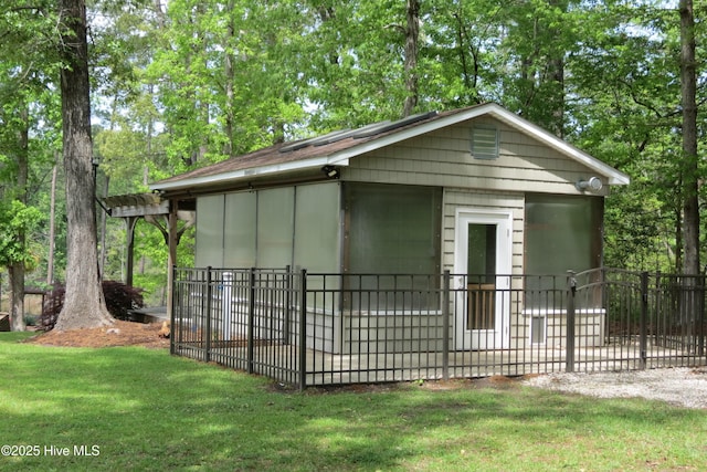 rear view of property with board and batten siding, an outdoor structure, fence, and a lawn