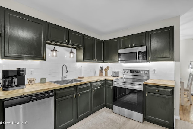 kitchen featuring tasteful backsplash, light wood-style flooring, wood counters, stainless steel appliances, and a sink