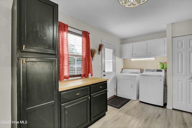 washroom with cabinet space, light wood-style flooring, and washer and clothes dryer