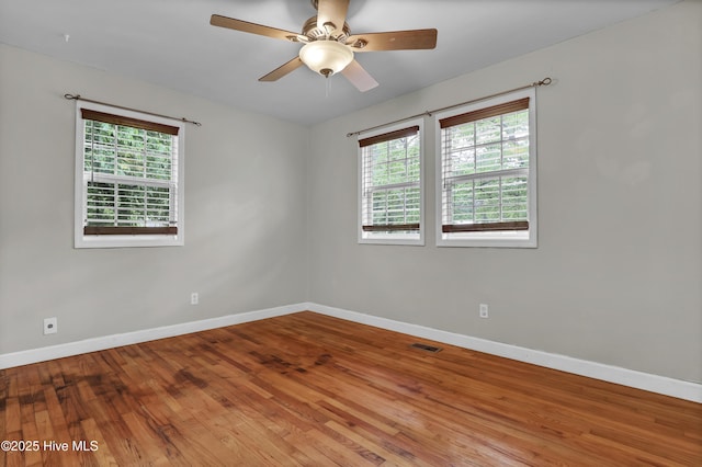 unfurnished room with baseboards, wood finished floors, and a wealth of natural light