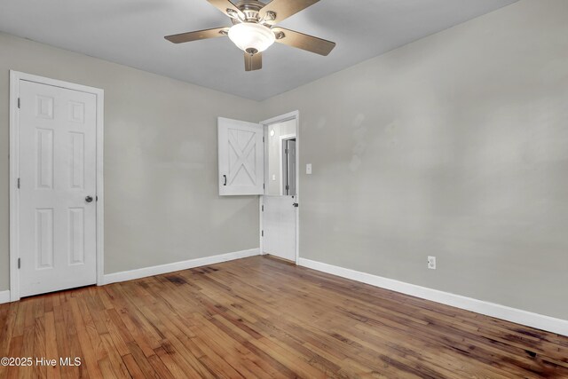 unfurnished room with baseboards, wood finished floors, and a ceiling fan