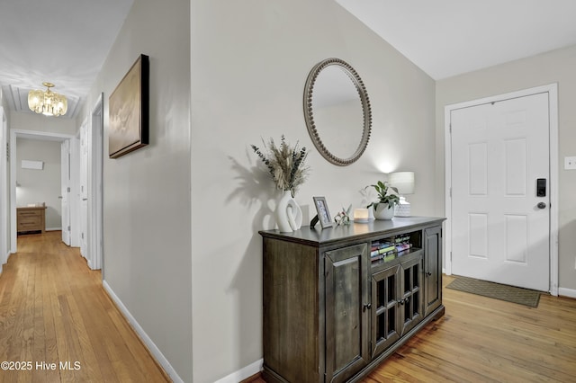 foyer entrance with baseboards, a notable chandelier, and light wood finished floors
