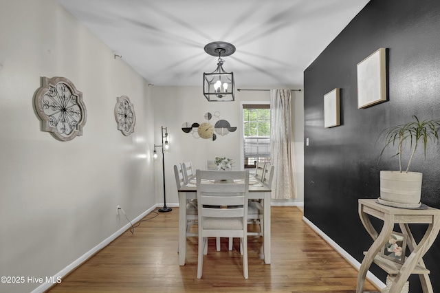 dining room with wood finished floors, a notable chandelier, and baseboards