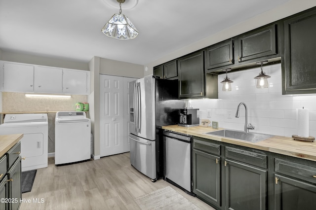 kitchen with tasteful backsplash, appliances with stainless steel finishes, washer and clothes dryer, and a sink