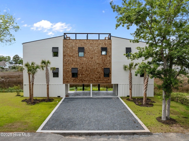 exterior space featuring driveway, a front lawn, and a carport