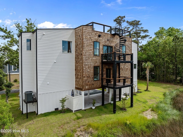 rear view of house with a balcony, a yard, and central AC