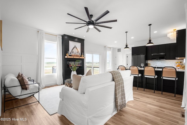 living area featuring light wood finished floors, ceiling fan, plenty of natural light, and visible vents