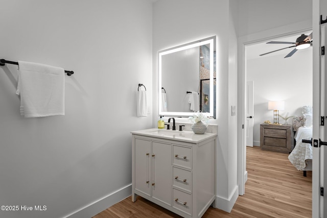 bathroom featuring connected bathroom, wood finished floors, baseboards, and a ceiling fan