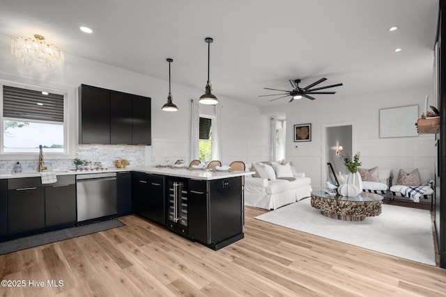 kitchen with open floor plan, dark cabinets, a sink, and stainless steel dishwasher