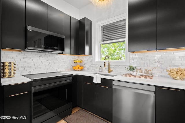 kitchen featuring dark cabinets, a sink, black appliances, backsplash, and light countertops