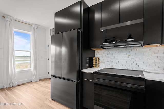 kitchen featuring dark cabinets, refrigerator, and light countertops