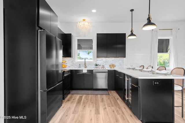 kitchen featuring black fridge, dark cabinetry, light countertops, and dishwasher