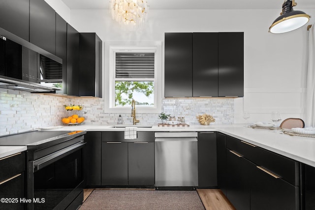 kitchen with dishwasher, dark cabinetry, a sink, tasteful backsplash, and electric range