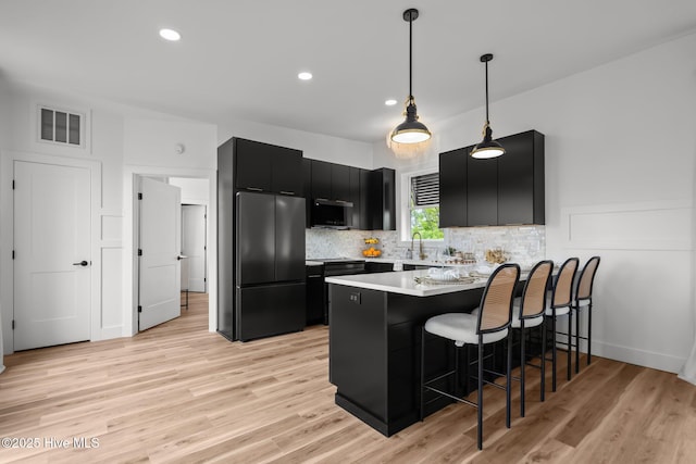 kitchen with freestanding refrigerator, dark cabinetry, visible vents, a peninsula, and light countertops