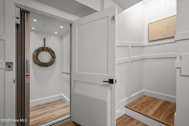 interior space featuring baseboards, light wood-type flooring, elevator, and recessed lighting