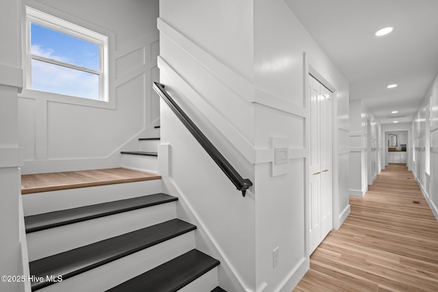 staircase with wood finished floors and recessed lighting