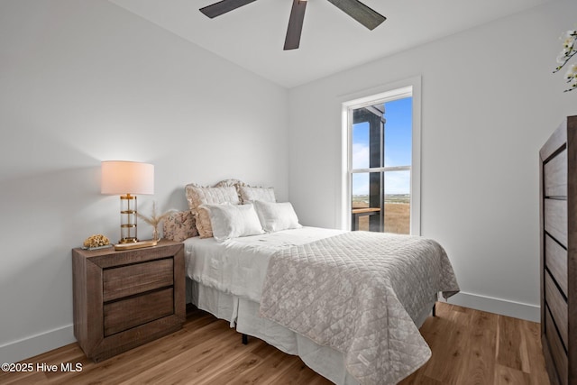 bedroom featuring light wood-type flooring, baseboards, and ceiling fan