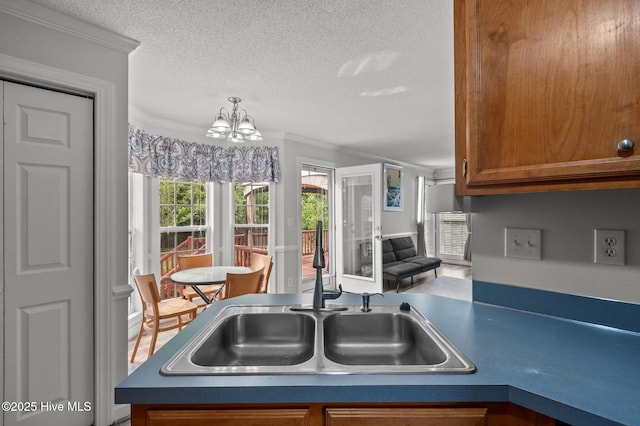 1114 Stone Creek Dr, Greenville, NC 27858 - kitchen featuring a sink, brown cabinets, a textured ceiling, a chandelier, and ornamental molding