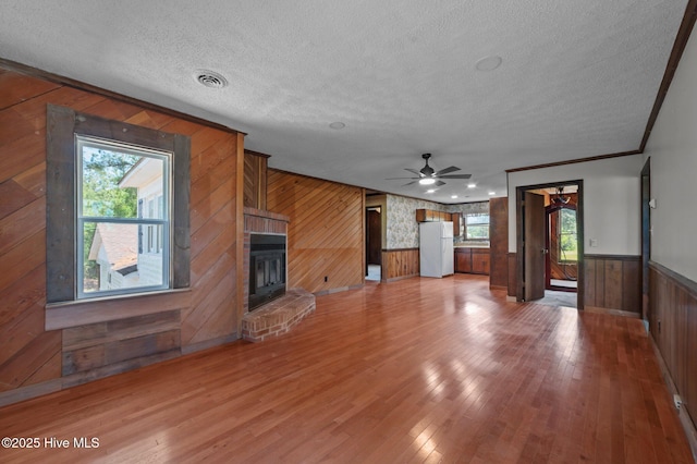 9952 US Highway 17 S, Vanceboro, NC 28586 - unfurnished living room with ceiling fan, a textured ceiling, visible vents, wood walls, and a glass covered fireplace