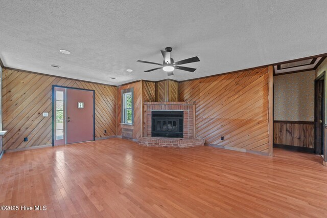 9952 US Highway 17 S, Vanceboro, NC 28586 - unfurnished living room with ceiling fan, a fireplace, a textured ceiling, wood walls, and hardwood / wood-style floors