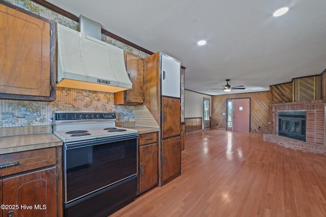 9952 US Highway 17 S, Vanceboro, NC 28586 - kitchen with a brick fireplace, range with electric stovetop, ceiling fan, light countertops, and exhaust hood