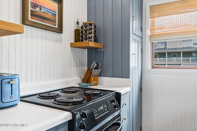 kitchen with light countertops, open shelves, and electric range