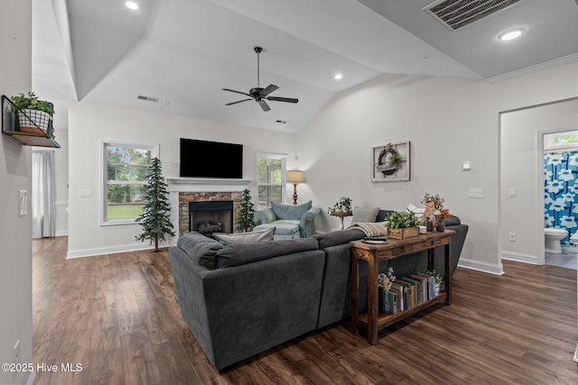 living area featuring a ceiling fan, visible vents, a fireplace, vaulted ceiling, and baseboards