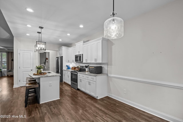 kitchen with a kitchen island with sink, a breakfast bar area, a sink, white cabinets, and stainless steel appliances