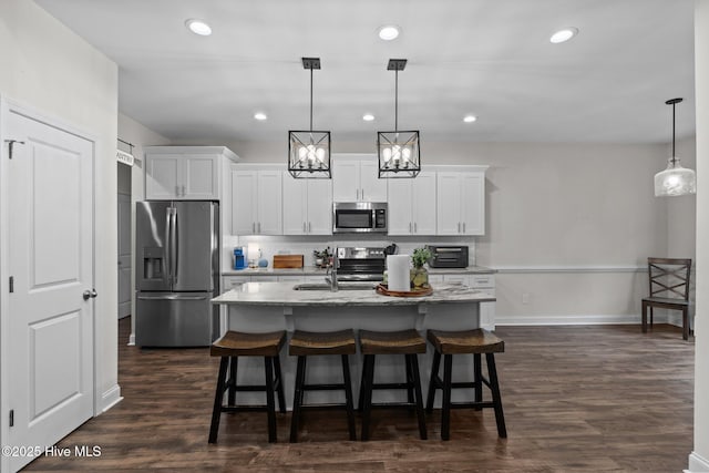 kitchen with dark wood-style flooring, white cabinets, a breakfast bar, stainless steel appliances, and an island with sink