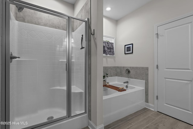 bathroom with baseboards, a shower stall, a bath, and wood finish floors