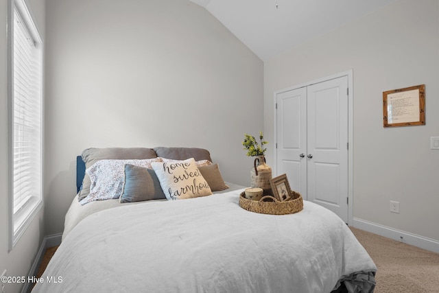 carpeted bedroom featuring a closet, baseboards, multiple windows, and vaulted ceiling