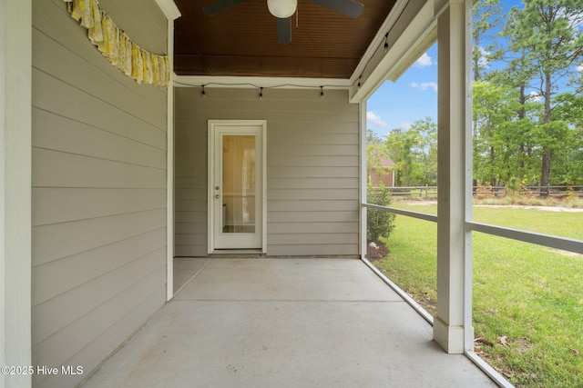 entrance to property featuring a lawn, fence, ceiling fan, and a patio area
