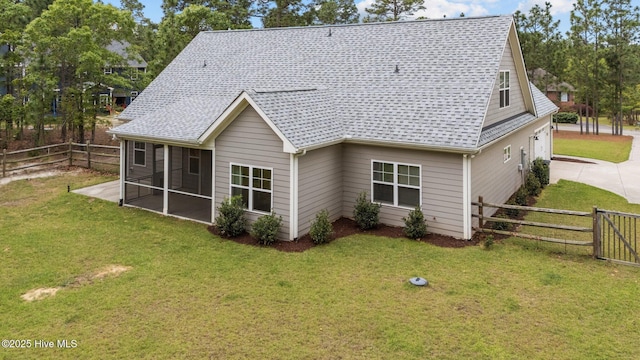 rear view of property with a sunroom, a fenced backyard, roof with shingles, and a yard